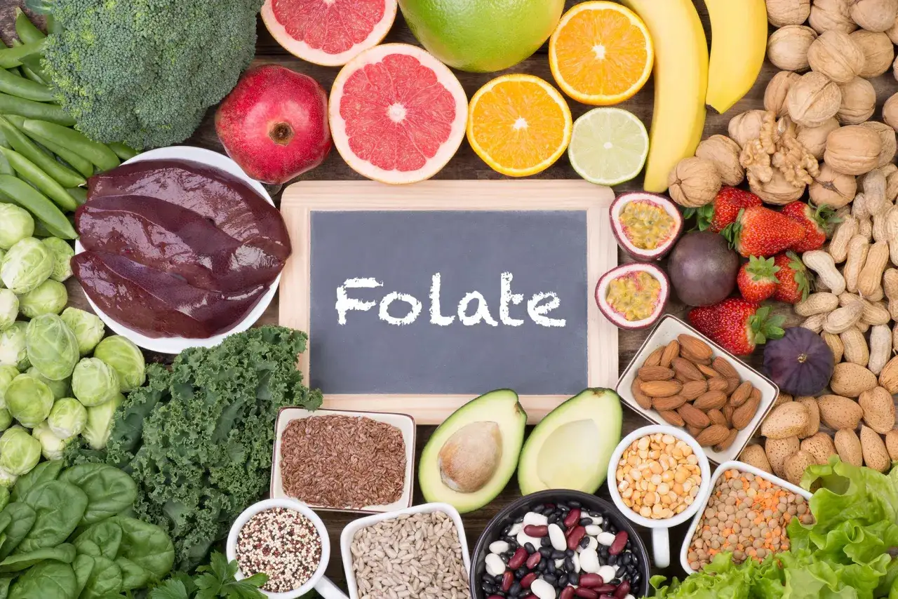 Kwas foliowy, jaka to witamina? Na zdjęciu widać bogactwo produktów bogatych w foliany: wątróbkę, warzywa liściaste, owoce cytrusowe, orzechy i nasiona.